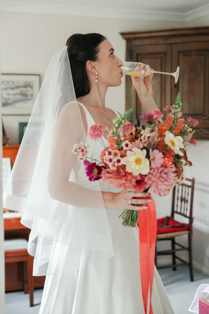 Bride having a sip of prosecco before leaving for wedding ceremony