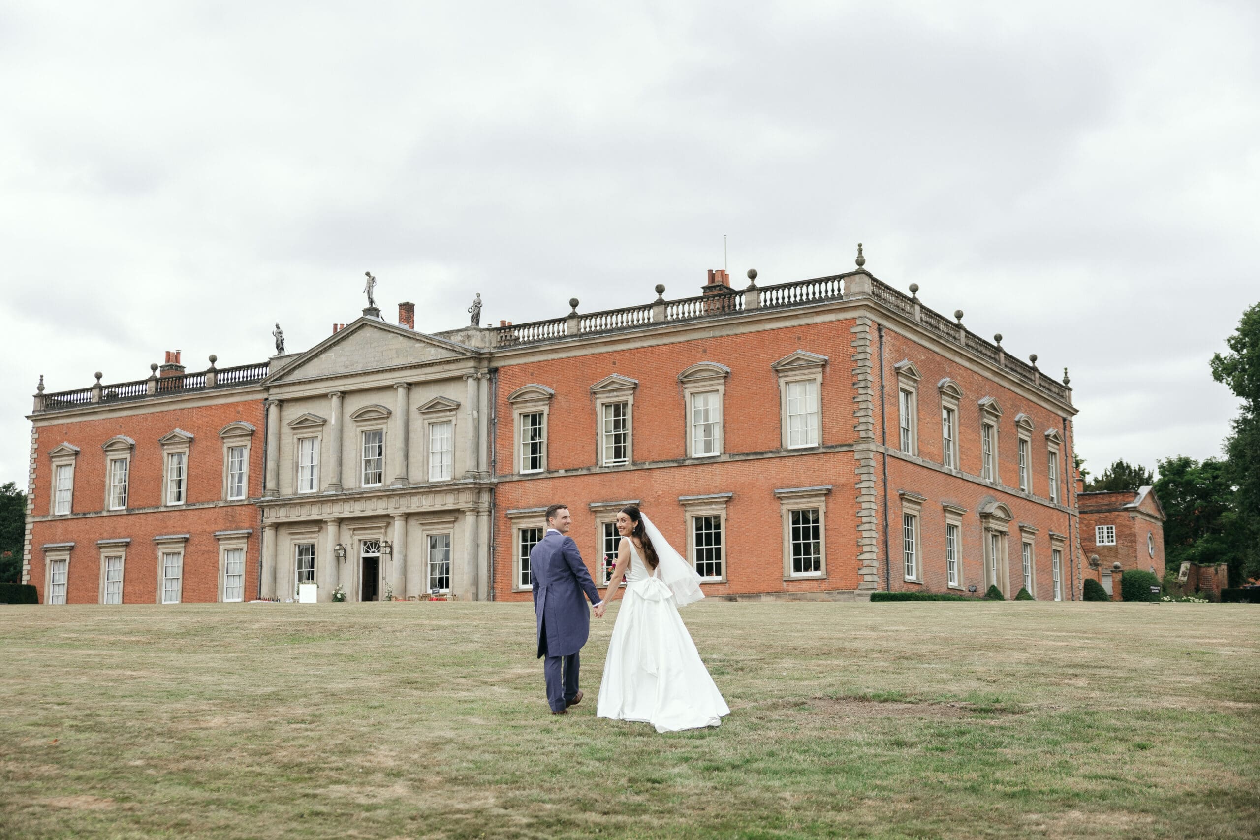 Bride and groom walking towards Staunton Harold Hall