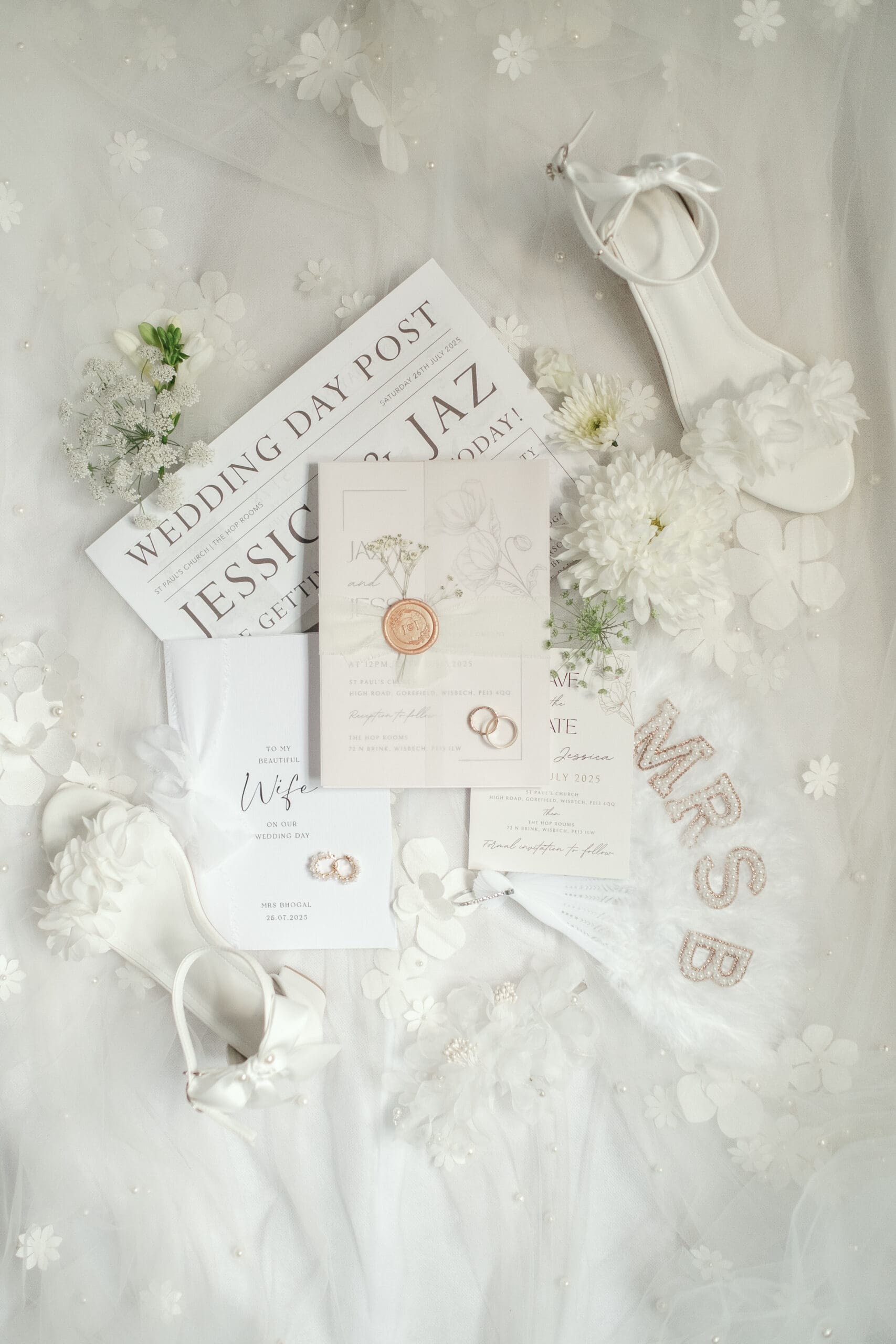 Flat lay of morning wedding details including rings, stationery, and accessories